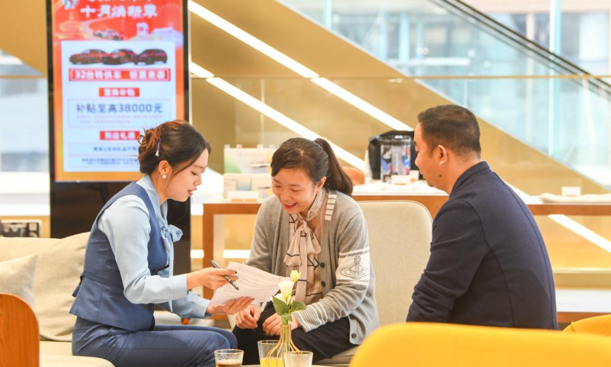 A staff member (L) introduces the policies related to car purchase subsidies to consumers at a 4S store in Chongqing, southwest China, Oct. 17, 2024. (Xinhua/Wang Quanchao)