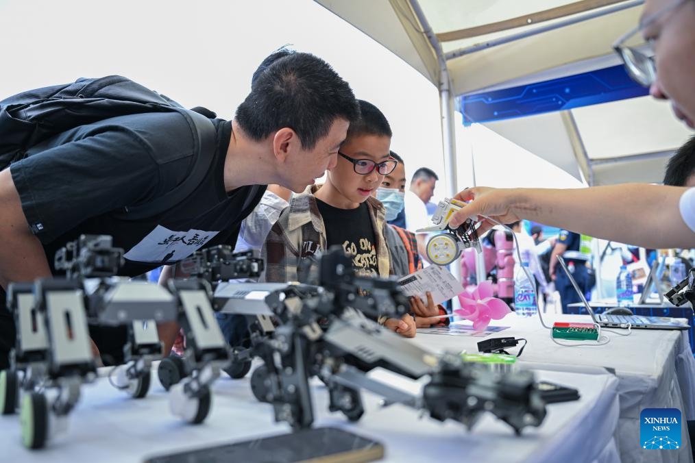 Visitors learn about a desktop robot during the world robot carnival in Wuhan, central China's Hubei Province, June 2, 2025. The event kicked off here on Monday, featuring nearly 100 robots including pet robots, make-up robots, robotics band, etc. People interacted with the robots to experience the charm of technology-empowered life. (Xinhua/Du Zixuan)
