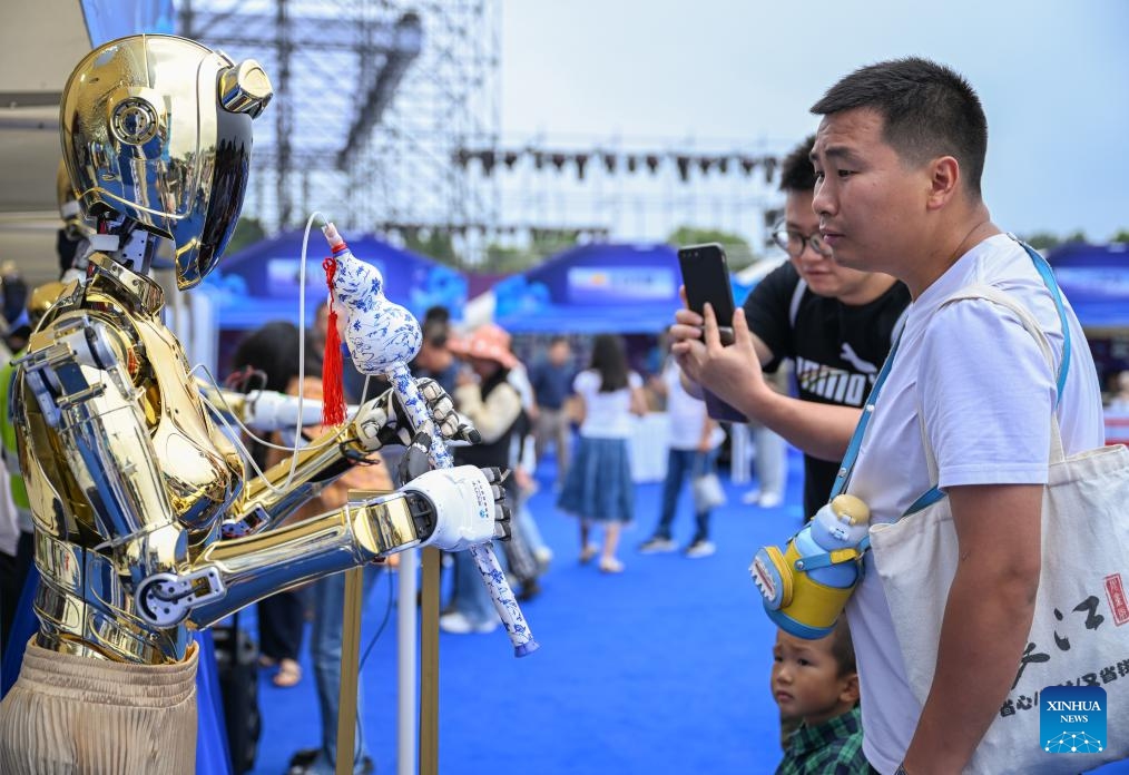 Visitors learn about a robotic bandsman during the world robot carnival in Wuhan, central China's Hubei Province, June 2, 2025. The event kicked off here on Monday, featuring nearly 100 robots including pet robots, make-up robots, robotics band, etc. People interacted with the robots to experience the charm of technology-empowered life. (Xinhua/Du Zixuan)