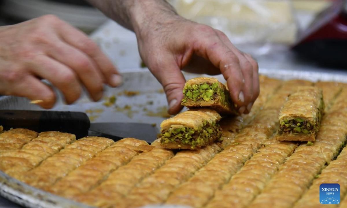 A worker arranges pieces of baklava at a sweets shop ahead of Eid al-Adha in Damascus, Syria, on June 4, 2025. Traditional sweets are widely prepared and exchanged during Eid celebrations. (Photo by Ammar Safarjalani/Xinhua)