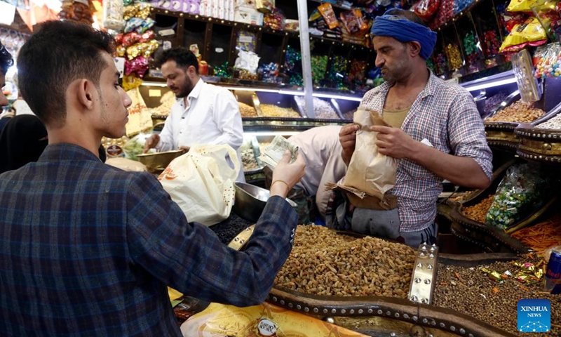 A customer buys sweets in preparation for the Muslim festival of Eid al-Adha, or the Feast of Sacrifice, at a market in Sanaa, Yemen, on June 2, 2025. (Photo by Mohammed Mohammed/Xinhua)