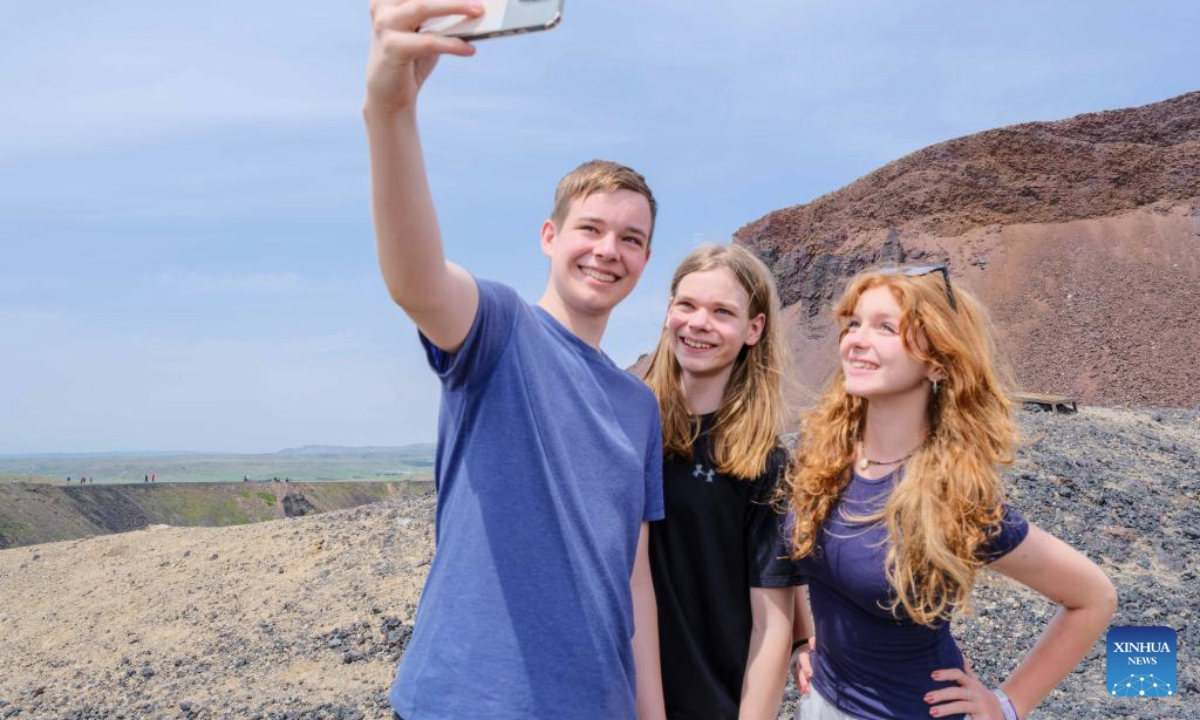 Tourists from the U.S. take a selfie in front of a volcano of the Ulanhada volcano cluster in Qahar Right Wing Rear Banner of Ulanqab, north China's Inner Mongolia Autonomous Region, June 17, 2025. The Ulanhada volcano cluster boasts special geological landscapes such as volcanoes and lava landform. With summer's arrival, it has entered the peak tourist season. (Xinhua/Ma Jinrui)