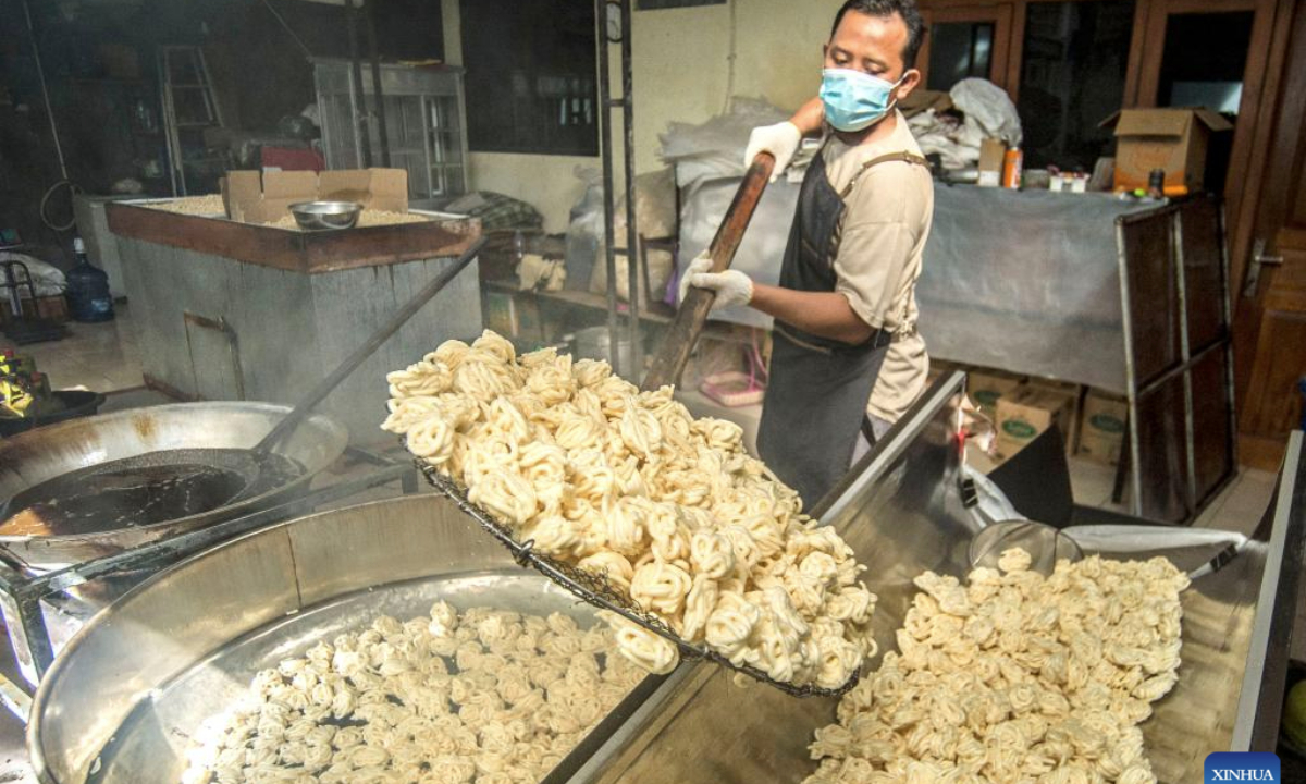 A worker loads fish crackers from pan for oil dripping at a home workshop in Maguwoharjo, Yogyakarta, Indonesia, June 18, 2025. (Photo by Agung Supriyanto/Xinhua)