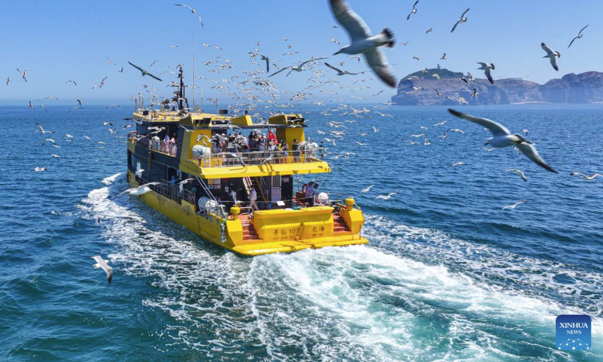 A drone photo taken on June 23, 2025 shows tourists enjoying a boat tour in Rongcheng City, east China's Shandong Province. (Photo by Li Xinjun/Xinhua)