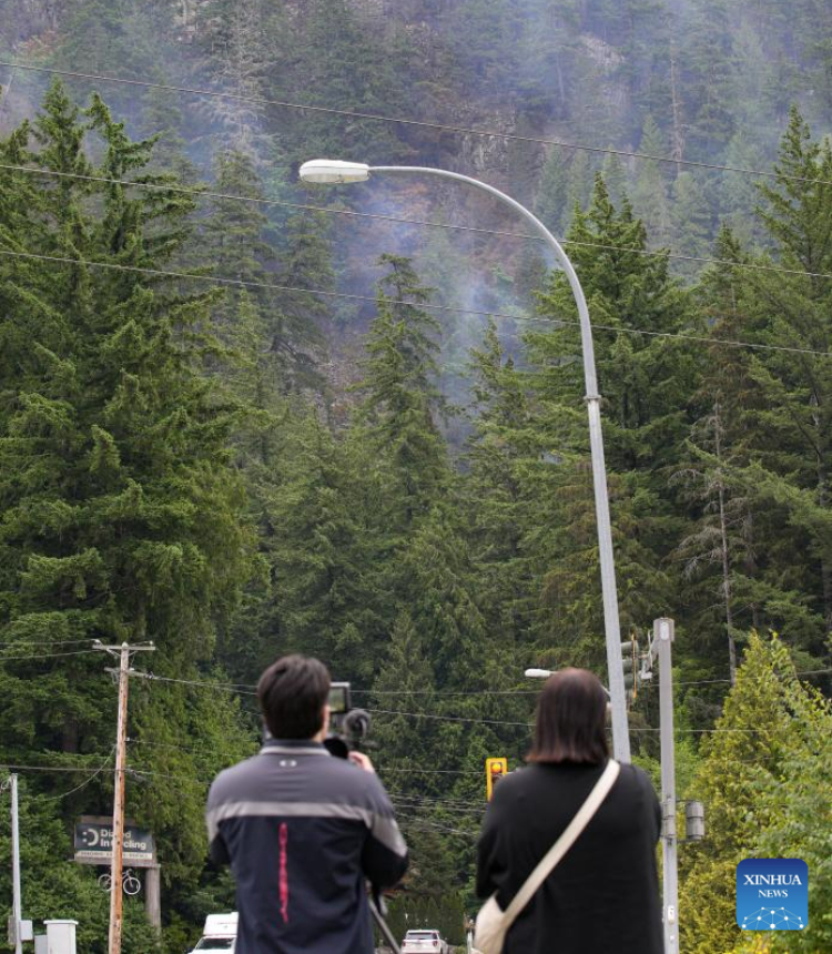 People watch the wildfire from a distance in Squamish, British Columbia, Canada, on June 12, 2025. Wildfire in Squamish has spread to 54 hectares in size, prompting an evacuation of the nearby area, according to BC Wildfire Service on Thursday. (Photo by Harrison Ha/Xinhua)