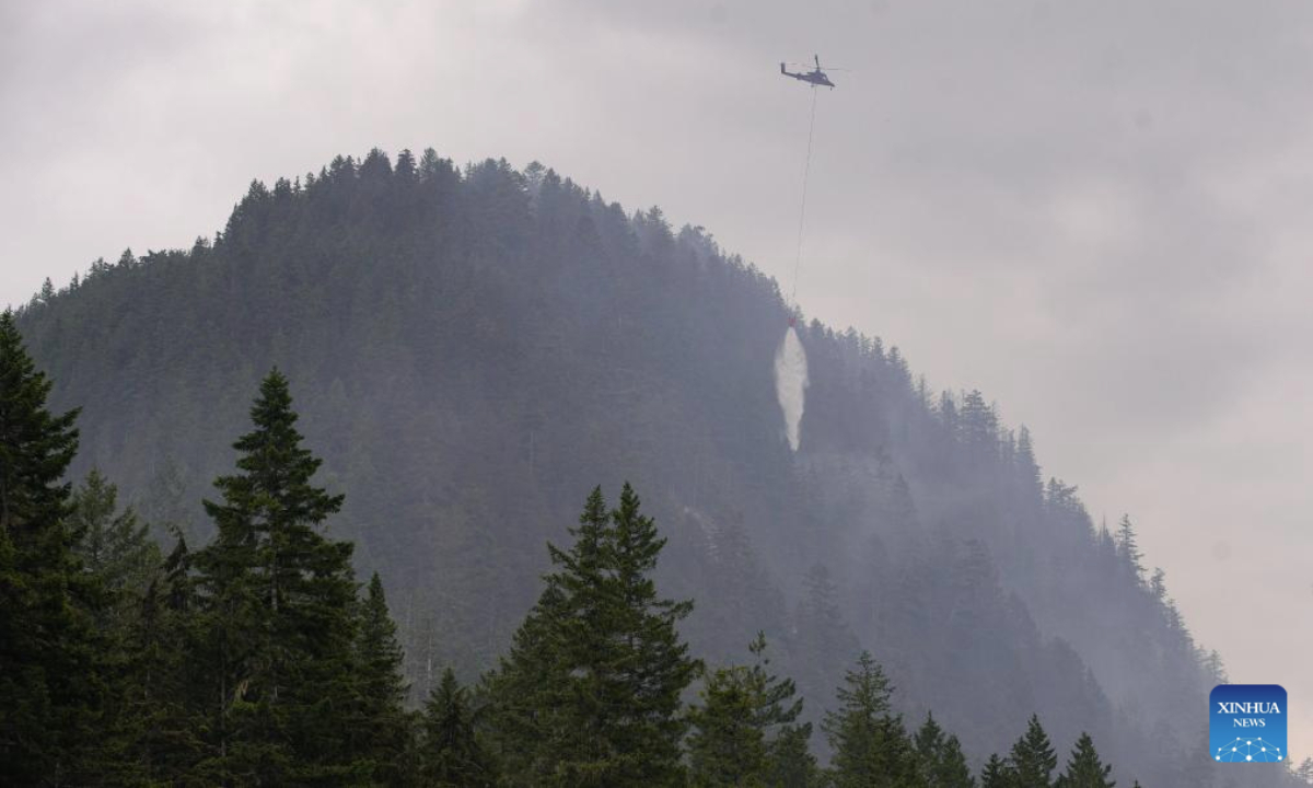 A helicopter drops water on the wildfire in Squamish, British Columbia, Canada, on June 12, 2025. Wildfire in Squamish has spread to 54 hectares in size, prompting an evacuation of the nearby area, according to BC Wildfire Service on Thursday. (Photo by Harrison Ha/Xinhua)

