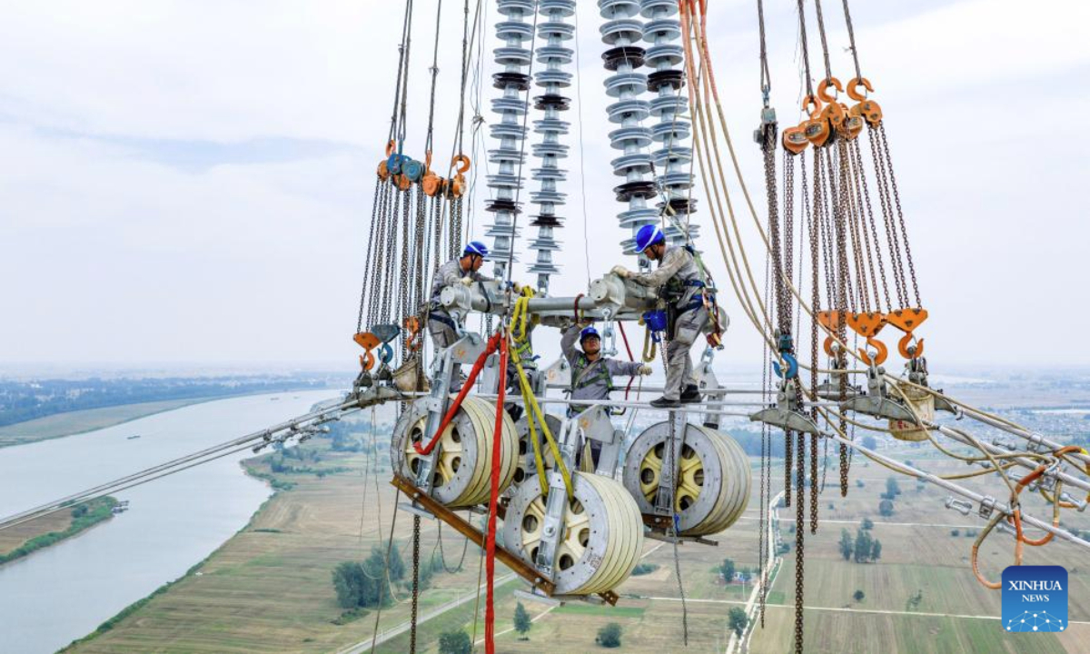 A drone photo shows staff members working on a power transmission line in Fengyang County, east China's Anhui Province, June 11, 2025. The 500 kV power transmission project from Xiangjian to Ludao in Anhui Province successfully completed the Huaihe River crossing on Wednesday. The two 193-meter towers on both sides of Huaihe River have realized a tremendous crossing distance of 1,578 meters. (Xinhua/Liu Junxi)