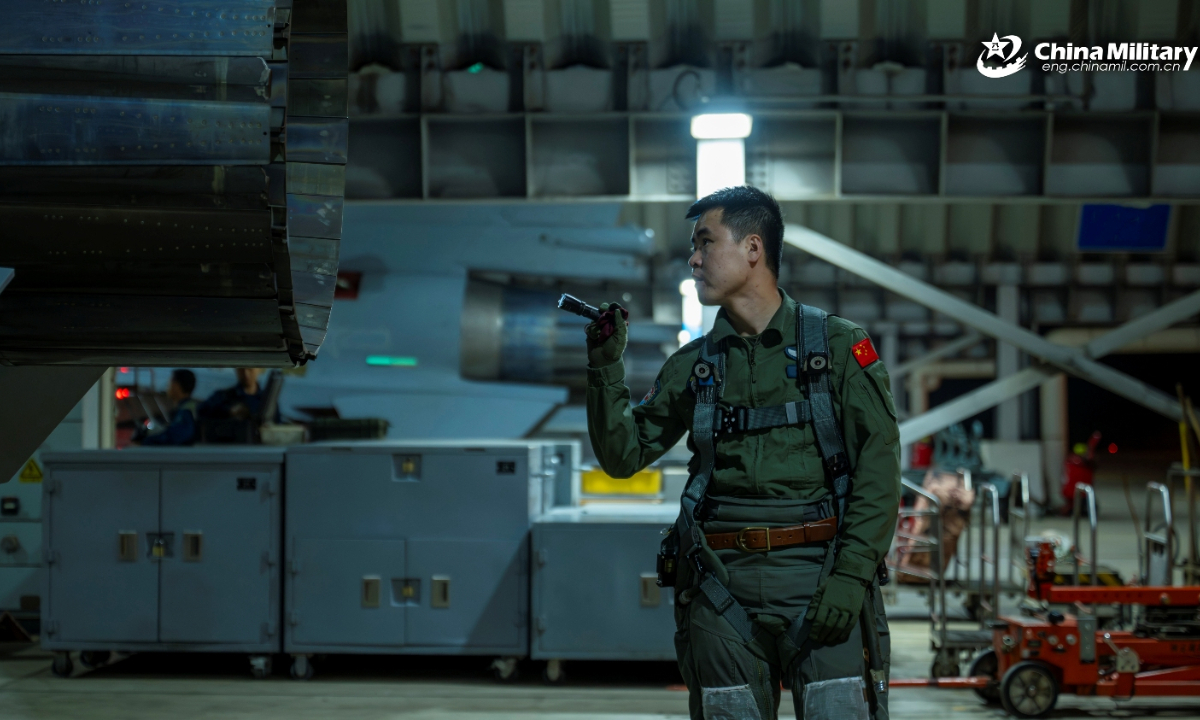 A pilot assigned to an aviation brigade with the air force under the Chinese PLA Southern Theater Command inspects the engine nozzle of a fighter jet during a nighttime flight training exercise in recent days. (eng.chinamil.com.cn/Photo by Xiao Rui)