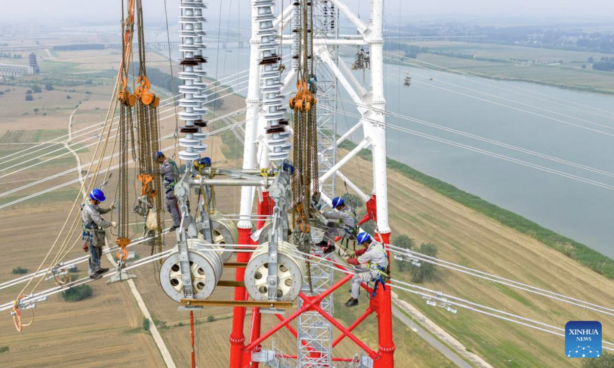 A drone photo shows staff members working on a power transmission line in Fengyang County, east China's Anhui Province, June 11, 2025. The 500 kV power transmission project from Xiangjian to Ludao in Anhui Province successfully completed the Huaihe River crossing on Wednesday. The two 193-meter towers on both sides of Huaihe River have realized a tremendous crossing distance of 1,578 meters. (Photo by Zhao Xianfu/Xinhua)