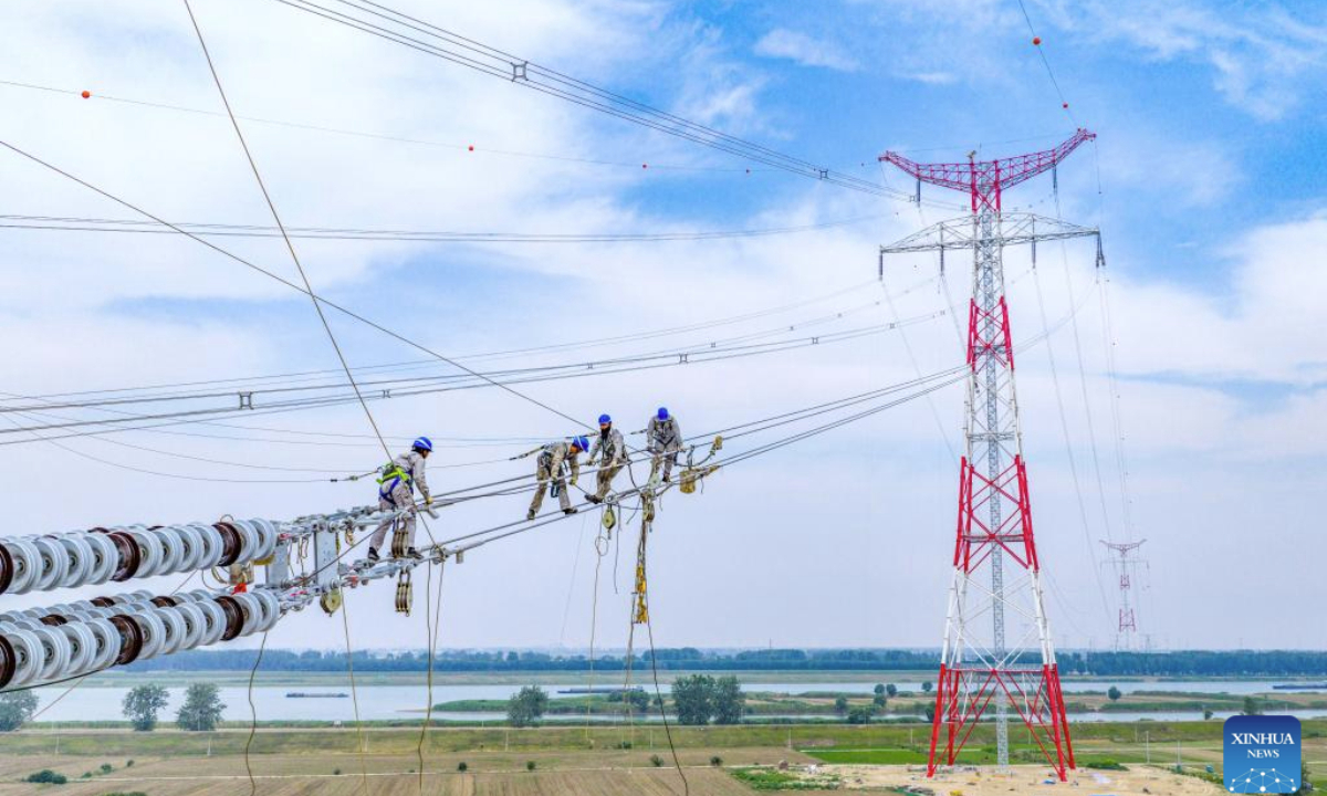A drone photo shows staff members working on a power transmission line in Fengyang County, east China's Anhui Province, June 11, 2025. The 500 kV power transmission project from Xiangjian to Ludao in Anhui Province successfully completed the Huaihe River crossing on Wednesday. The two 193-meter towers on both sides of Huaihe River have realized a tremendous crossing distance of 1,578 meters. (Photo by Zheng Xianlie)