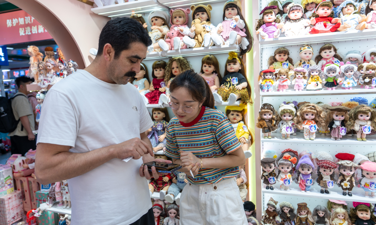 A foreign customer asks a shop owner about prices in the toy section of the Yiwu International Trade Market in Yiwu, East China's Zhejiang Province, on June 9, 2025. Foreign buyers keep arriving in 