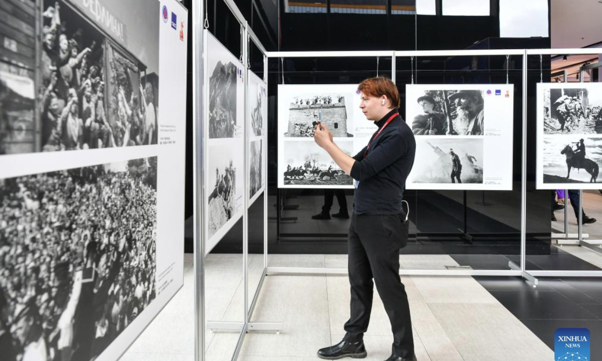 A visitor takes photos at a photo exhibition marking the 80th anniversary of the victory of the World Anti-Fascist War in St. Petersburg, Russia, June 19, 2025. Titled Immortal Merits, Eternal Memory, the exhibition was co-hosted by Xinhua News Agency and TASS news agency. (Xinhua/Cao Yang)
