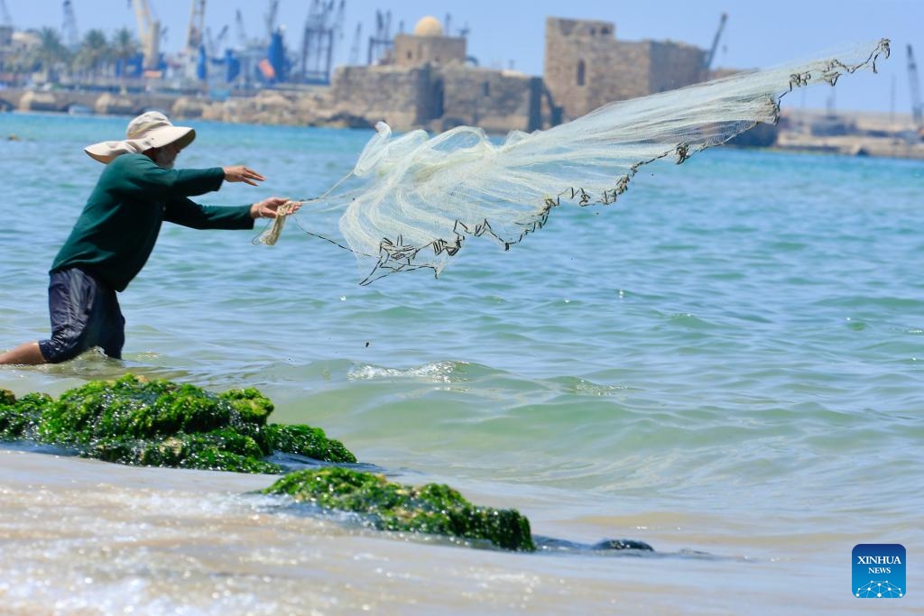 A man throws the net to catch fish during the Eid al-Adha holiday on the beach in Sidon, Lebanon, on June 7, 2025. (Photo: Xinhua)