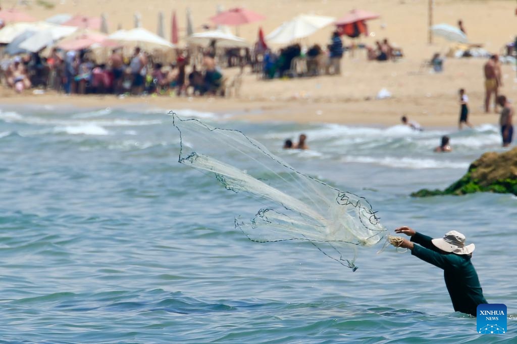 A man throws the net to catch fish during the Eid al-Adha holiday on the beach in Sidon, Lebanon, on June 7, 2025. (Photo: Xinhua)