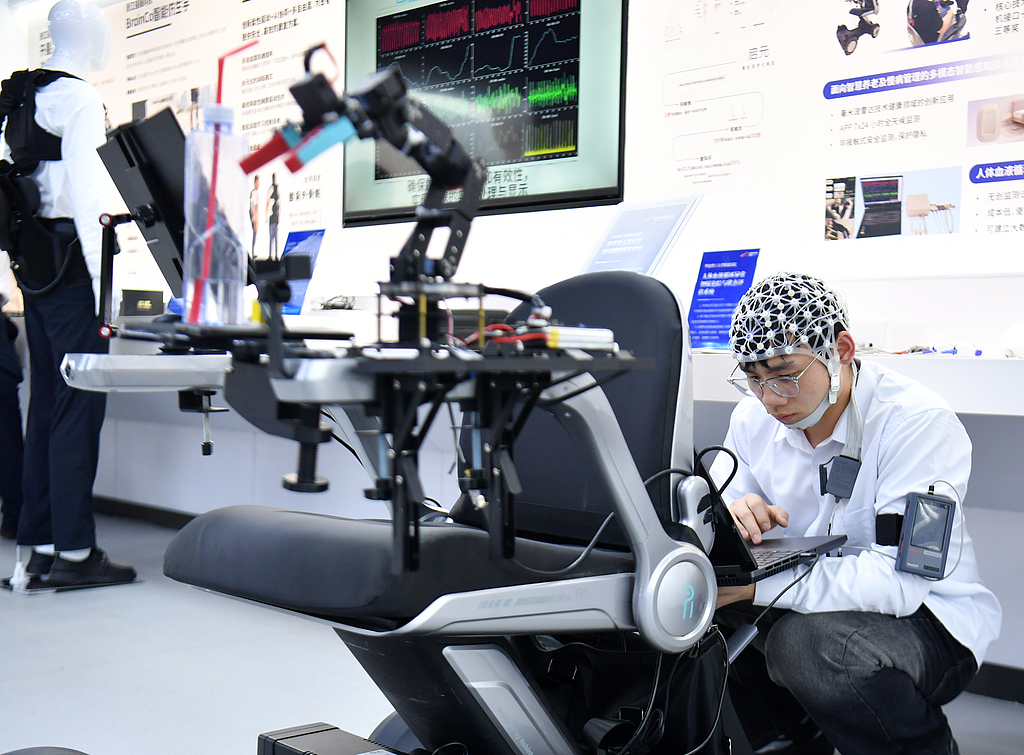 A staff member adjusts a multimodal human-computer interaction intelligent brain-controlled rehabilitation wheelchair at the second Xiong'an Future City Scenarios Gathering series in Xiong'an New Area, North China's Hebei Province, on June 10, 2025. Running through June 29, the event features high-tech competition finals across 11 critical fields, including smart agriculture, robotics, artificial intelligence vertical large models, and low-altitude transportation. Photo: VCG