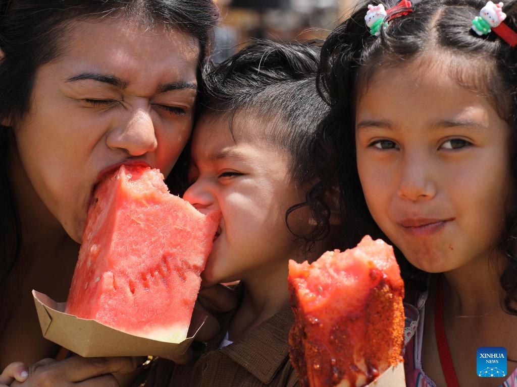 People pose for a photo with watermelon during the 2025 California Watermelon Festival at the Hansen Dam Park in Los Angeles, California, the United States, June 7, 2025. (Photo: Xinhua)