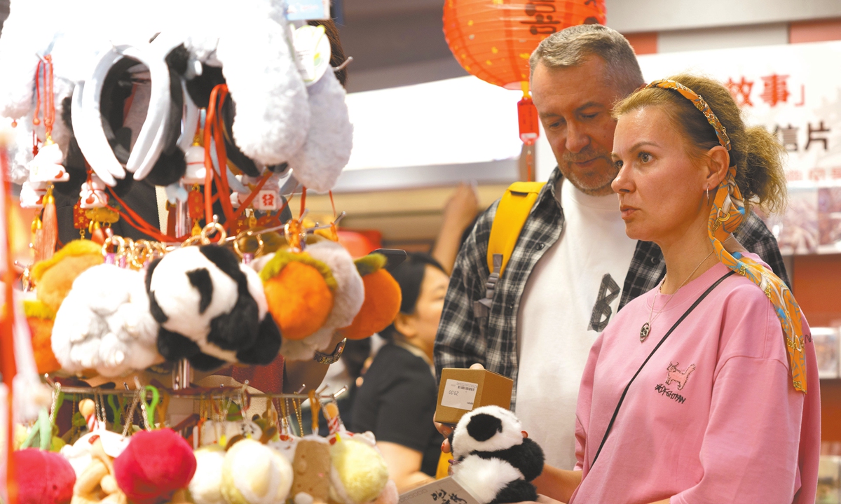 Foreign tourists pick souvenirs at the Nanluoguxiang Lane, a popular tourist site in Beijing, on May 16, 2025. Photo: VCG