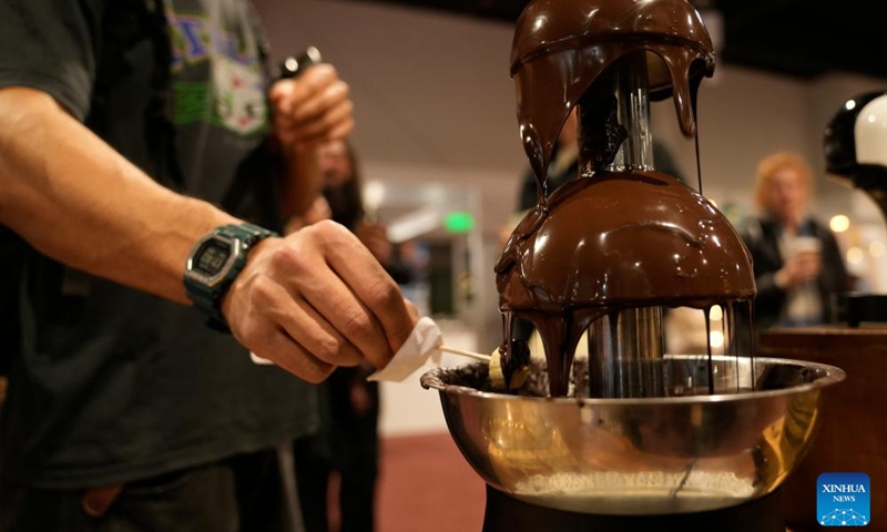 A visitor tries to make a fruit snack with chocolate during the International Alfajor Fair in Montevideo, Uruguay, June 13, 2025. The International Alfajor Fair kicked off on Friday at the Technological Laboratory of Uruguay (LATU) in the capital Montevideo and will run until June 15. Alfajor, a popular Latin American sweet, typically consists of a layer of dulce de leche (caramelized milk spread) sandwiched between two cookies and is coated in chocolate for a crumbly texture. It has developed distinct local variations and is especially beloved in Argentina, Uruguay, Peru and Chile.(Photo: Xinhua)