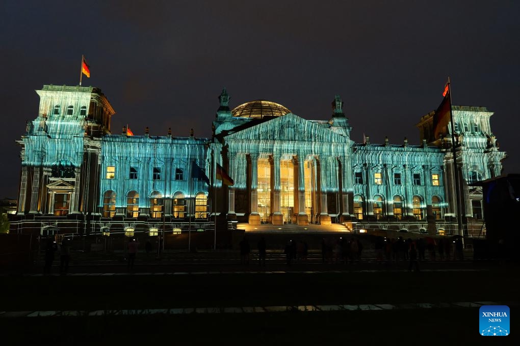 The Reichstag is seen illuminated in Berlin, Germany, June 15, 2025. In the midsummer nights of Berlin, the Reichstag is once again wrapped, not in fabric this time, but in light. From June 9 to June 20, 24 synchronized projectors illuminate the building's west facade, simulating the visual effect of massive fabric wrapping and unveiling. The light show is designed to commemorate the 30th anniversary of Bulgarian-born artist Christo and his wife Jeanne-Claude's iconic 1995 artwork, Wrapped Reichstag. (Photo: Xinhua)