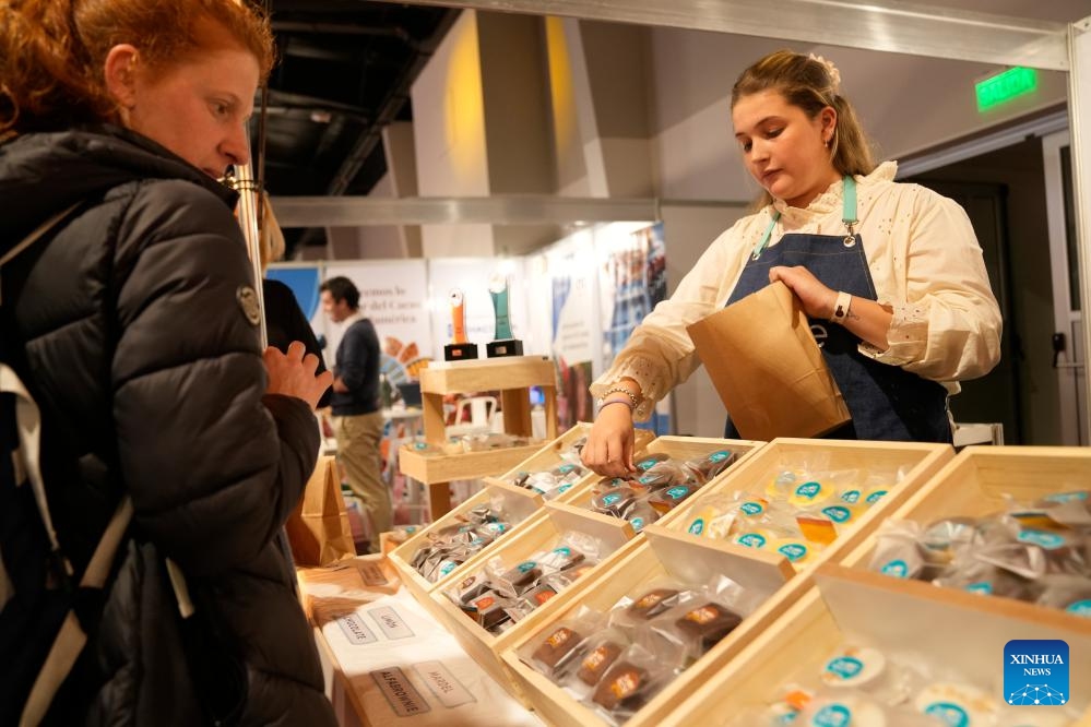 A visitor (L) buys Alfajors during the International Alfajor Fair in Montevideo, Uruguay, June 13, 2025. The International Alfajor Fair kicked off on Friday at the Technological Laboratory of Uruguay (LATU) in the capital Montevideo and will run until June 15. Alfajor, a popular Latin American sweet, typically consists of a layer of dulce de leche (caramelized milk spread) sandwiched between two cookies and is coated in chocolate for a crumbly texture. It has developed distinct local variations and is especially beloved in Argentina, Uruguay, Peru and Chile.(Photo: Xinhua)