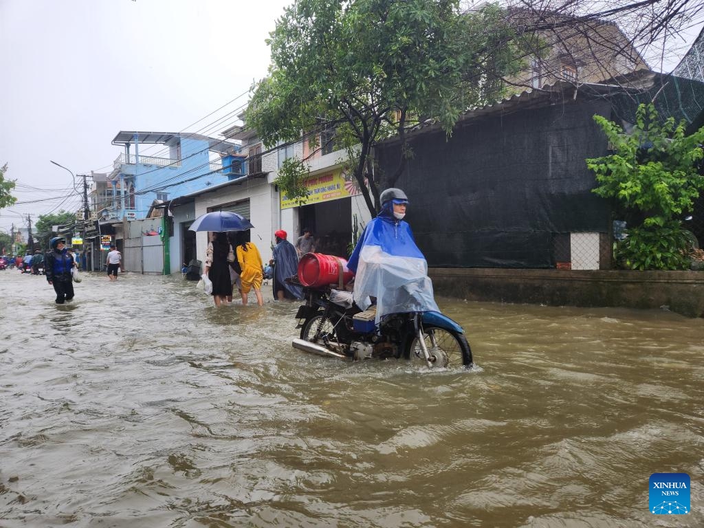 People wade through flood water in Hue city, central Vietnam, June 13, 2025. At least six people were killed and another remains missing in central Vietnam due to torrential rains and flooding triggered by Typhoon Wutip, the Vietnam Disaster and Dyke Management Authority said Sunday. (Photo: Xinhua)