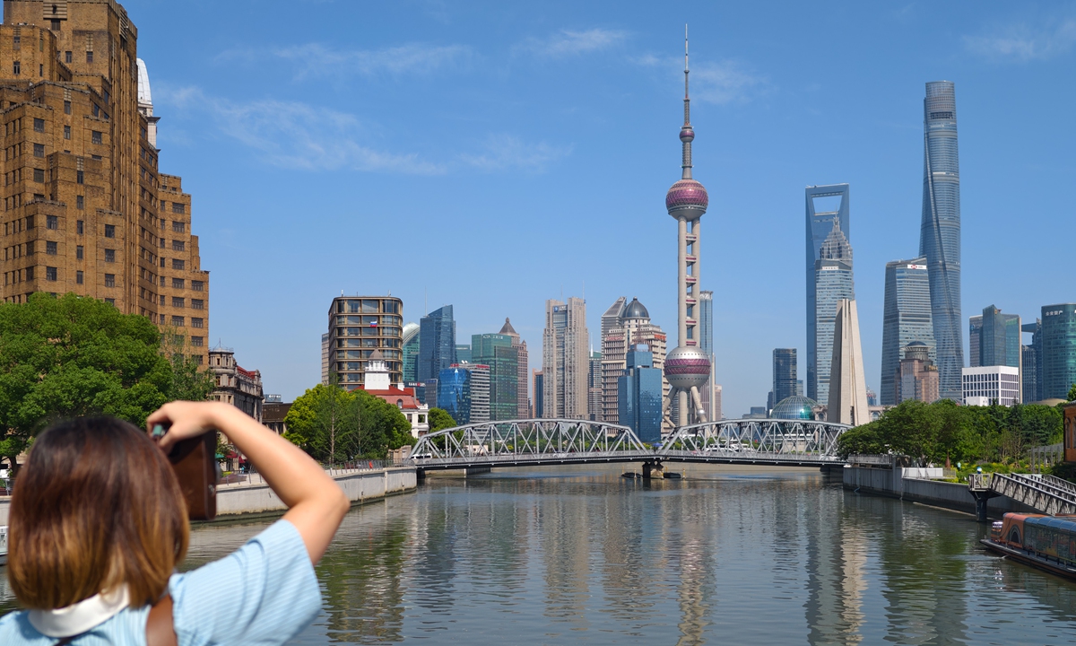 A tourist takes a picture of the view of the Suzhou River with landmark buildings in Lujiazui in the background in Shanghai on June 16, 2025. Photo: IC
