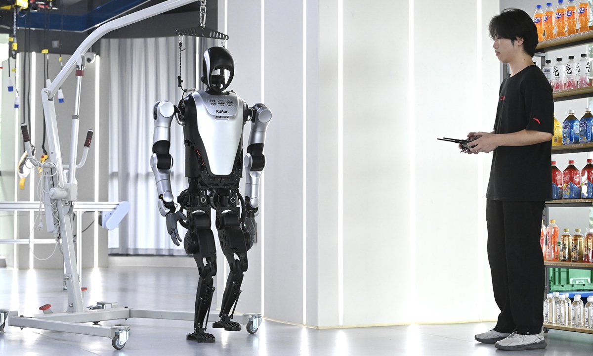 A staff member trains a humanoid robot at an embodied intelligence robot data collection and pretraining center in Hefei, East China's Anhui Province on June 19, 2025. At the facility, robots learn to understand and replicate human behavior through remote control operations, starting with basic motion imitation and advancing to the execution of complex tasks. Photo: VCG