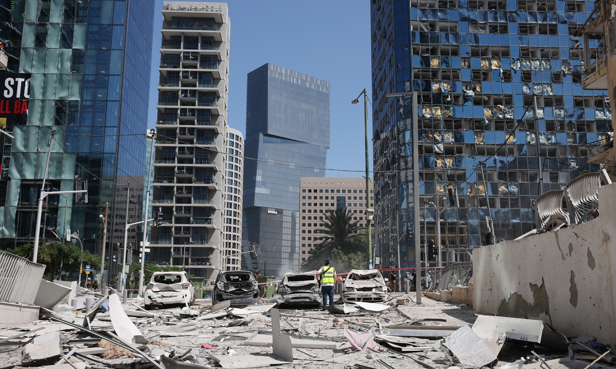 An Israeli police officers stands among debris near damaged cars at the site of an Iranian missile strike in a residential area in Ramat Gan, central Israel on June 19 2025. Photo: VCG