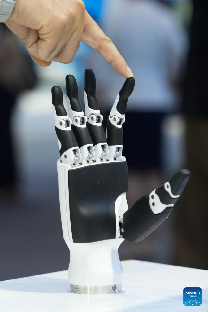 A visitor touches the finger of a humanoid hand at the Zhongguancun Exhibition Center in Beijing, capital of China, June 20, 2025. (Photo: Xinhua)