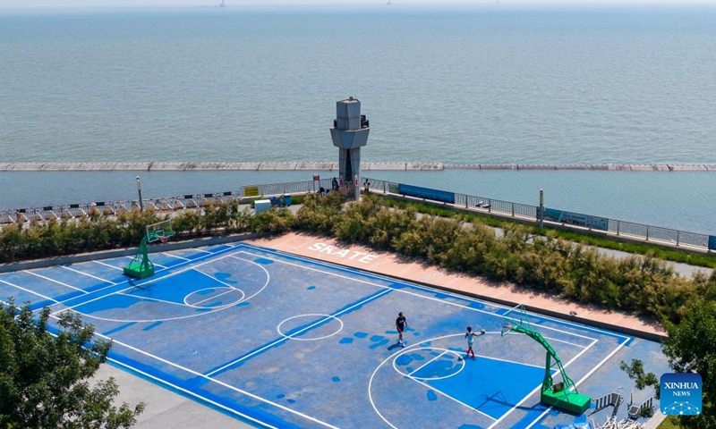 A drone photo taken on June 21, 2025 shows people playing basketball at a seaside park in Binhai New Area in north China's Tianjin. In recent years, Binhai New Area in Tianjin has made great efforts to protect ecological environment and upgraded the layout of parks. Several seaside landmarks in Binhai have become popular tourist destinations. (Photo: Xinhua)