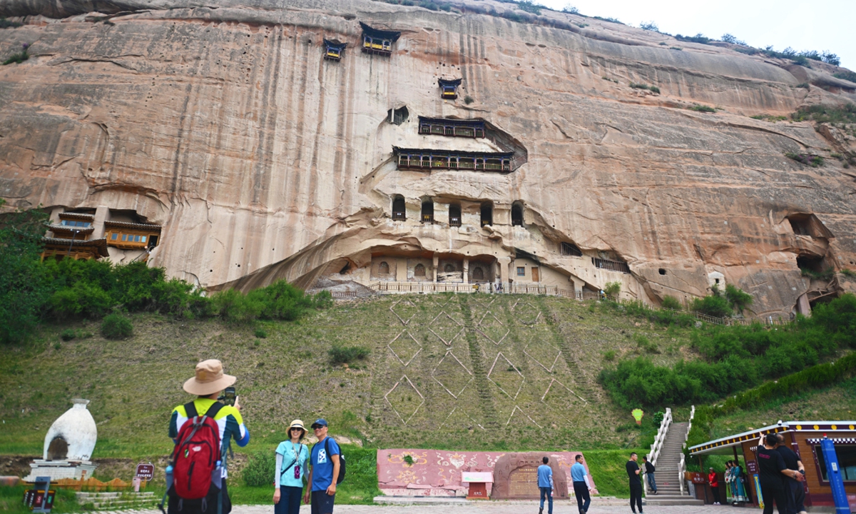 Tourists take photos in front of the Mati Temple Grottoes in Zhangye, Northwest China's Gansu Province, on June 23, 2025. Carved during the Northern Liang period of the Sixteen Kingdoms era (304-439), the Mati Temple Grottoes are regarded as one of the three great Buddhist art treasure troves of the Hexi Corridor, alongside the Mogao Caves in Dunhuang and the Yulin Caves in Guazhou. Photo: VCG