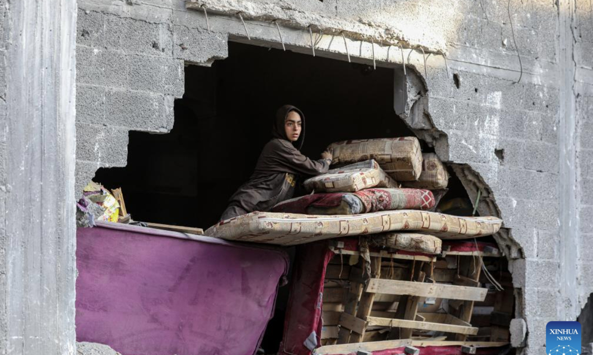 A Palestinian woman arranges items inside a damaged building after an Israeli airstrike at the Shati refugee camp, west of Gaza City, on June 26, 2025. (Photo by Rizek Abdeljawad/Xinhua)