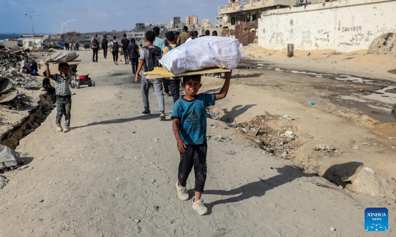 A Palestinian child carries a bag of collected firewood at a temporary shelter amid a long-time shortage of cooking gas and fuel in northern Gaza City, on June 24, 2025. (Photo: Xinhua)