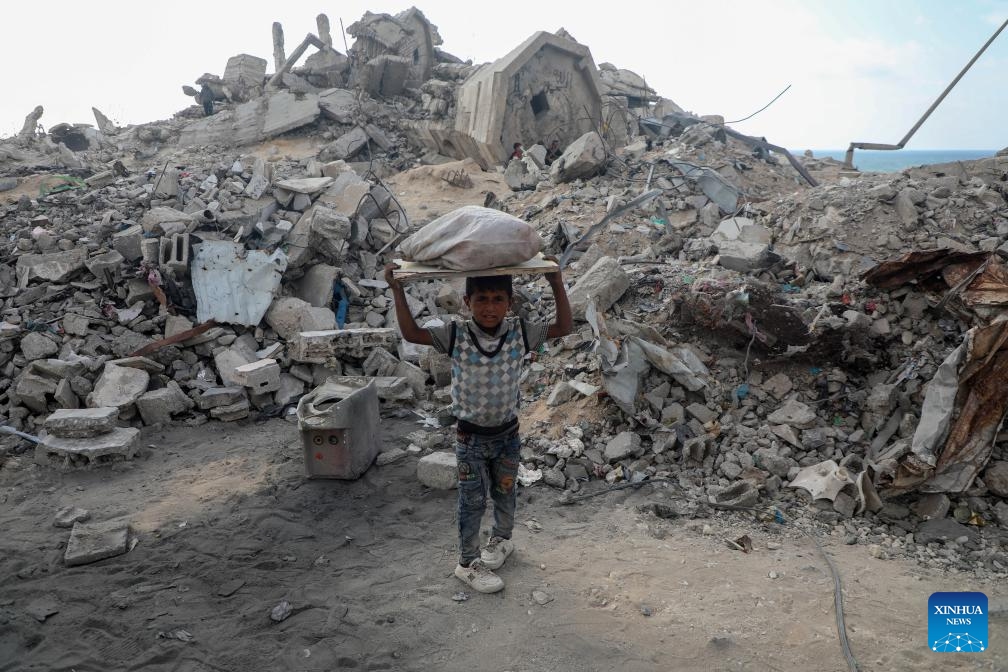 A Palestinian child carries a bag of collected firewood at a temporary shelter amid a long-time shortage of cooking gas and fuel in northern Gaza City, on June 24, 2025. (Photo: Xinhua)