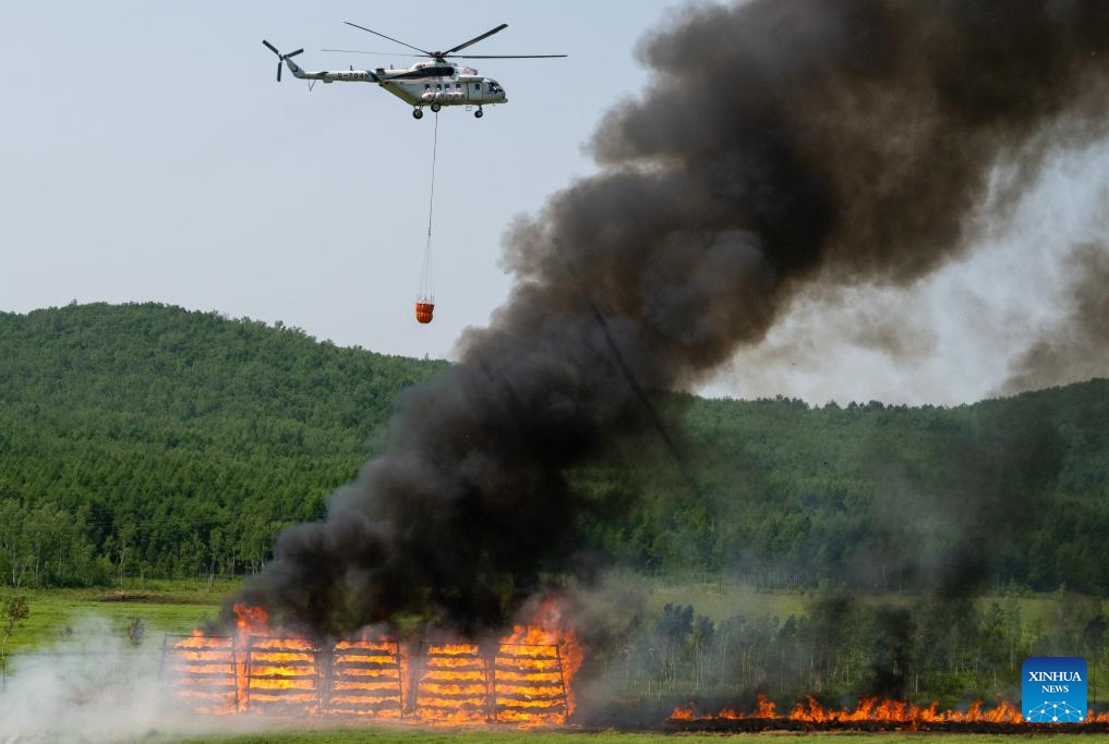 A fire-fighting helicopter carries water to battle a fire during a drill in the Dahinggan Mountains, northeast China's Heilongjiang Province, June 24, 2025. Local fire brigades conducted a fire drill in the Dahinggan Mountains on Tuesday to improve their preparedness and response mechanism. The drill featured four typical scenarios, namely emergence response, fighting primitive forest fires, fighting fuel storage tank fires, and fighting high-rise building fires. (Photo: Xinhua)