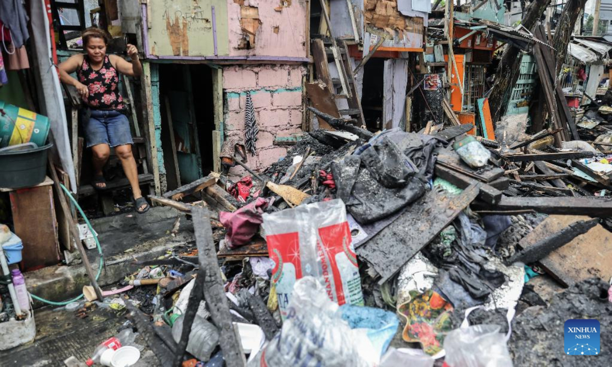 A woman returns to her charred home after a fire at a slum area in Manila, the Philippines, July 2, 2025. (Xinhua/Rouelle Umali)