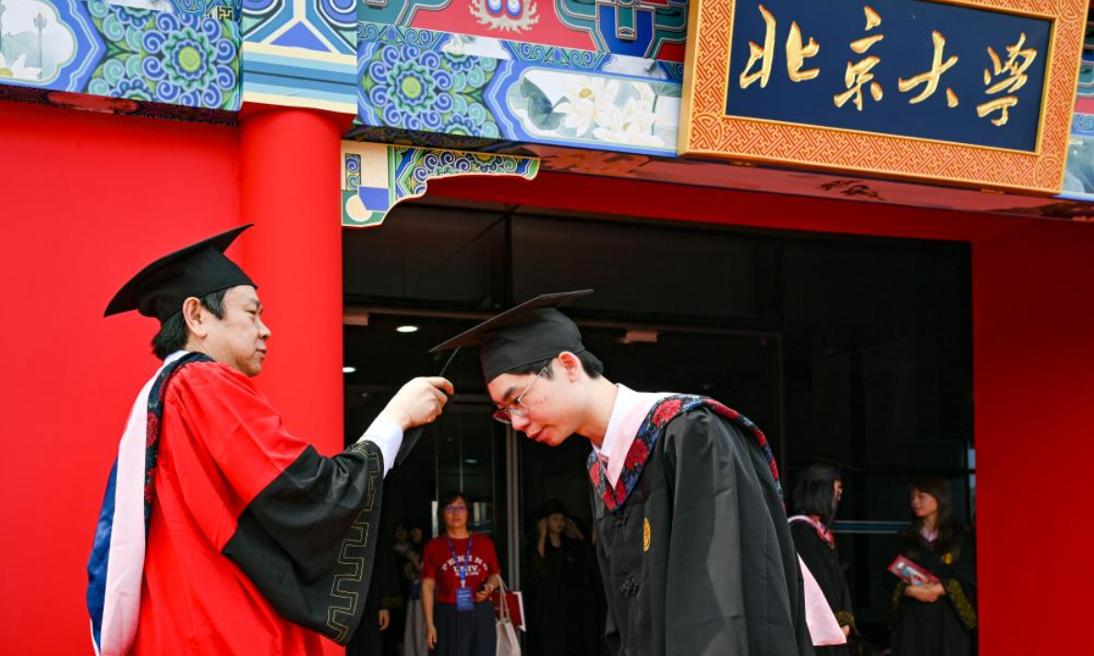 Liu Qiao, dean of Peking University's Guanghua School of Management, turns the tassel for a graduate at Peking University in Beijing, capital of China, July 2, 2025. Peking University held the graduation ceremony on Wednesday and conferred bachelor's degrees to more than 4,000 graduates. (Xinhua/Chen Shuo)