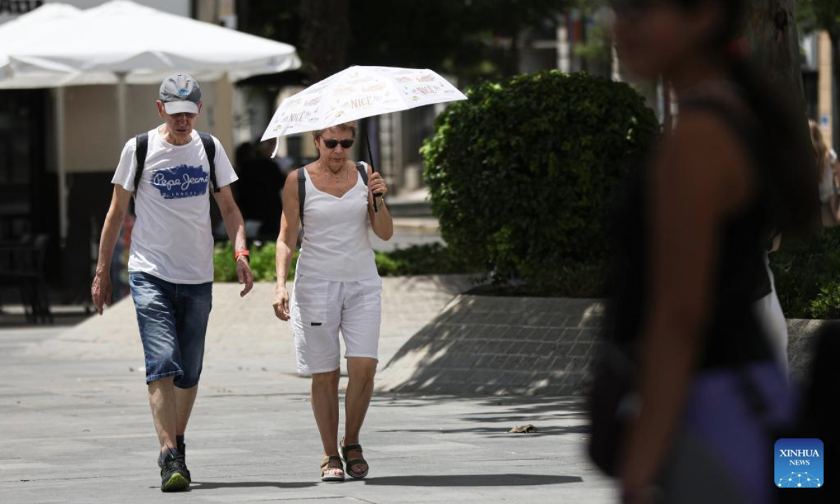 People walk with a parasol in Seville, Spain, July 2, 2025. Spain continues to endure a record-breaking heatwave. More than 100 monitoring stations of the Spanish meteorological agency AEMET registered temperatures exceeding 40 degrees Celsius during the first major heatwave of the year. (Xinhua/Li Jing)