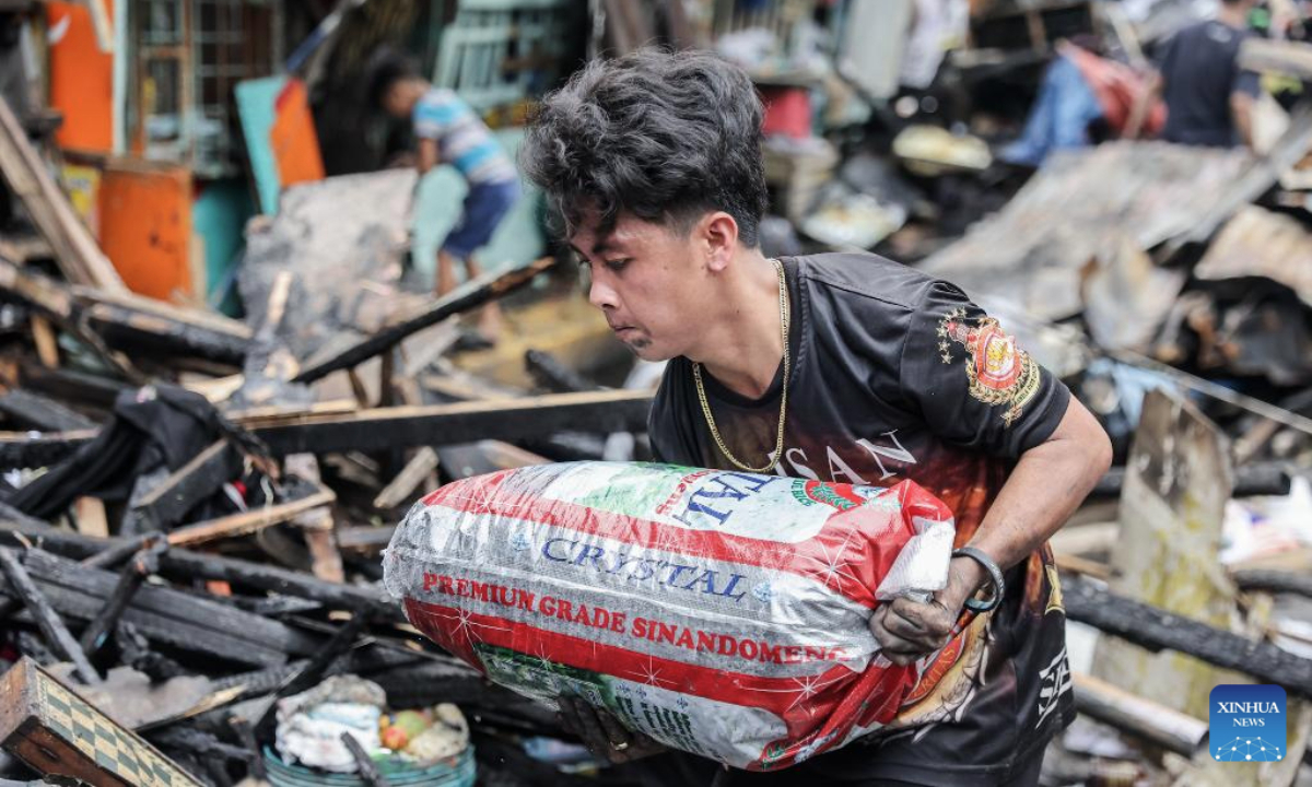 A man carries a sack of debris after clearing his charred home after a fire at a slum area in Manila, the Philippines, July 2, 2025. (Xinhua/Rouelle Umali)