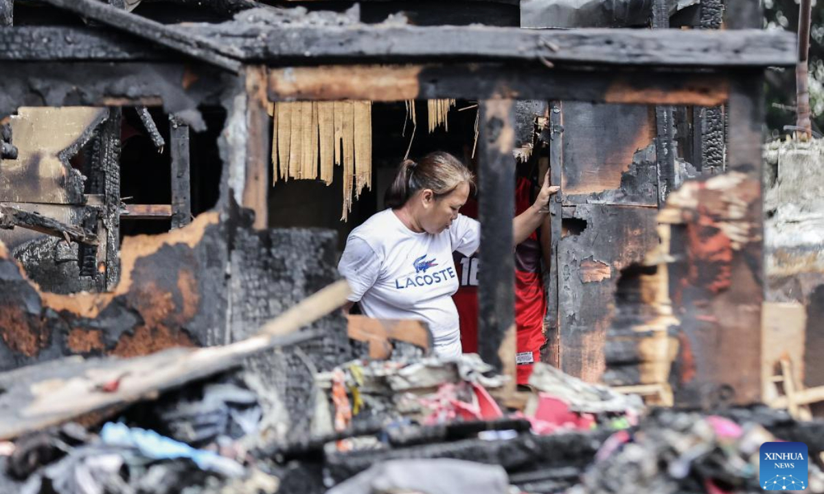 A woman returns to her charred home after a fire at a slum area in Manila, the Philippines, July 2, 2025. (Xinhua/Rouelle Umali)