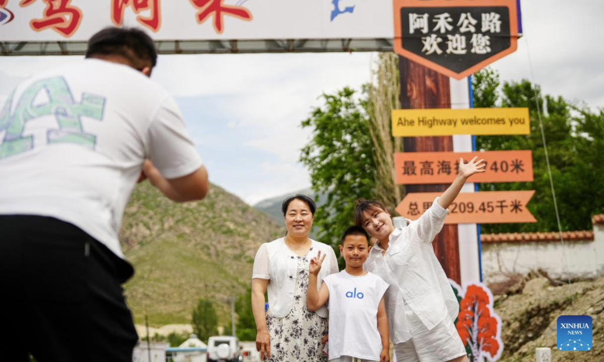 People pose for a photo alongside the Altay-Hemu highway in northwest China's Xinjiang Uygur Autonomous Region, June 30, 2025. The 209.45-kilometer-long highway linking Altay City and Hemu Village opened officially on Monday, connecting a number of tourist destinations. (Xinhua/Xu Hongyan)