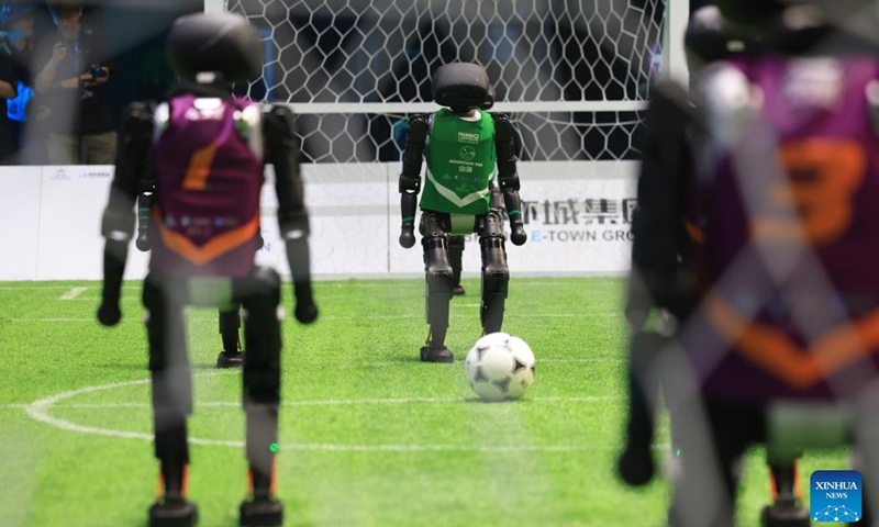 A robot player (C) of the Mountain Sea team from China Agricultural University competes during an AI-powered robot football match in Beijing, capital of China, June 28, 2025. A 3v3 robot football match, where all players were autonamous via artificial intelligence, concluded here Saturday. Four teams from three Chinese universities competed in the match, and the championship was garnered by the THU Robotics team from Tsinghua University. (Photo: Xinhua)