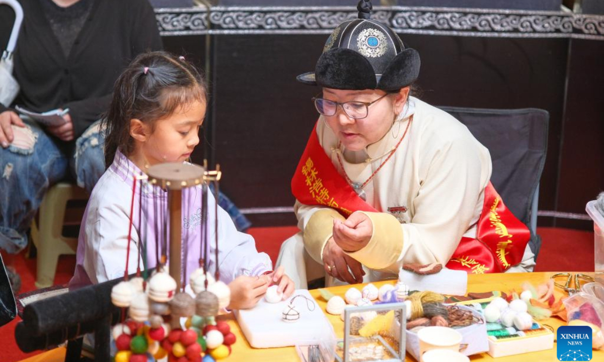 A kid experiences the traditional Mongolian felt making during a Nadam fair held in Xilinhot, Xilin Gol League, north China's Inner Mongolia Autonomous Region, July 19, 2025. The Nadam Fair opened here on Saturday, featuring night parade performances, intangible cultural heritage handicraft making events, and ethnic game experiences. The fair has effectively invigorated the summer tourism market, and attracted tourists to experience the charm of grassland culture. (Xinhua/Ma Jinrui)