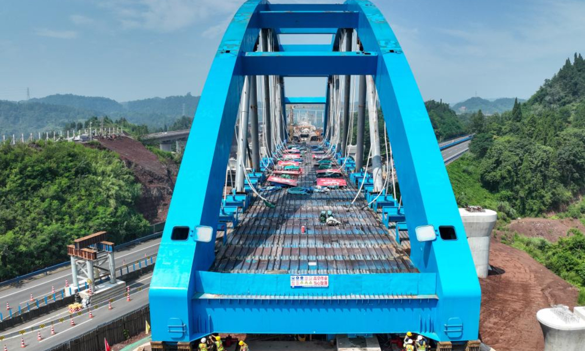 An aerial drone photo taken on July 11, 2025 shows a bridge of the Xi'an-Chongqing high-speed railway over an expressway under construction in Dazhou, southwest China's Sichuan Province. The main body of a bridge of Xi'an-Chongqing high-speed railway over an expressway linking Yingshan and Dazhou in Sichuan Province was smoothly lowered onto its piers on Friday. This marks the successful completion of the incremental launching construction for China's first large-span high-speed railway network arch bridge with tied girders, laying a solid foundation for the timely opening of the Xi'an-Chongqing high-speed railway. The bridge spans 443.1 meters in total length, and the constructed tied-arch bridge section weighs 2,600 tonnes, measuring 147 meters long and 17 meters wide, with an incremental launching displacement of approximately 146 meters over a 10-day construction period. (Xinhua/Wang Xi)