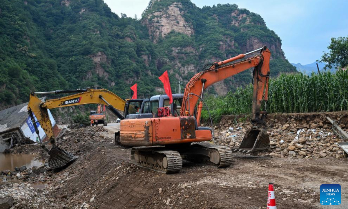 Staff members operate diggers to repair a damaged road in Liudaogou Village in Liudaohe Town, Xinglong County of north China's Hebei Province, Aug. 1, 2025. Affected by heavy rainfall, some roads and houses were damaged in several villages in Liudaohe Town. In recent days, local authorities have actively organized efforts to carry out relief operations to restore roads, power supply, and communication facilities, along with environmental disinfection measures. (Photo by Wang Liqun/Xinhua)