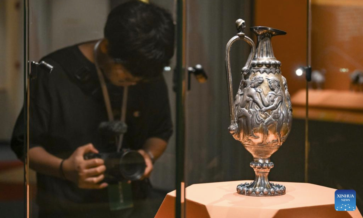 A media worker takes photos of a silver pot on display during a cultural relic exhibition at the Shanghai Museum East in east China's Shanghai, July 8, 2025. The exhibition, featuring over 300 cultural relics from Guyuan City of northwest China's Ningxia Hui Autonomous Region, opened in Shanghai on Tuesday. (Xinhua/Chen Haoming)