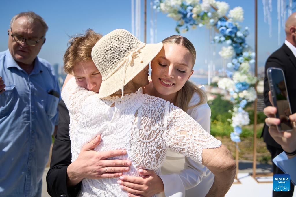 A couple receives blessings from their relatives and friends on a group wedding ceremony at Highland Park in Vladivostok, Russia, July 5, 2025. Three newlywed couples join in a group wedding ceremony here on Thursday, receiving blessings from families and friends. (Photo: Xinhua)