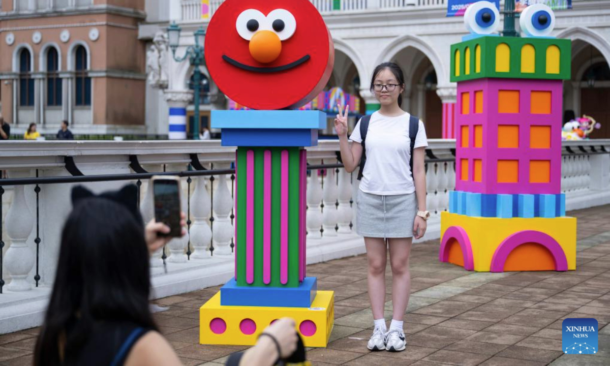 A tourist poses for a photo with an artwork on display during the special exhibition Dopamine: Fountain of Happiness at the Venetian Macao in Macao, south China, July 29, 2025. As a special exhibition of Art Macao: Macao International Art Biennale 2025, the event kicked off here on Tuesday. (Xinhua/Cheong Kam Ka)