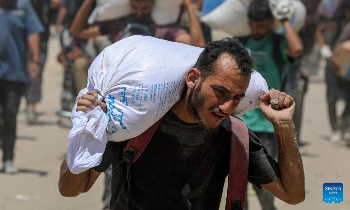Palestinians carry humanitarian aid in Beit Lahia, northern Gaza Strip, on Aug. 1, 2025. (Photo by Rizek Abdeljawad/Xinhua)