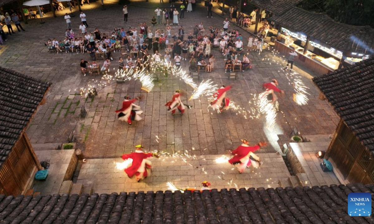 A drone photo taken on July 12, 2025 shows visitors watching a performance at a scenic spot in Youyang Tujia and Miao Autonomous County, southwest China's Chongqing Municipality. High temperature during the summer vacation has triggered new vitality of cooling economy across the country. (Photo by Qiu Hongbin/Xinhua)
